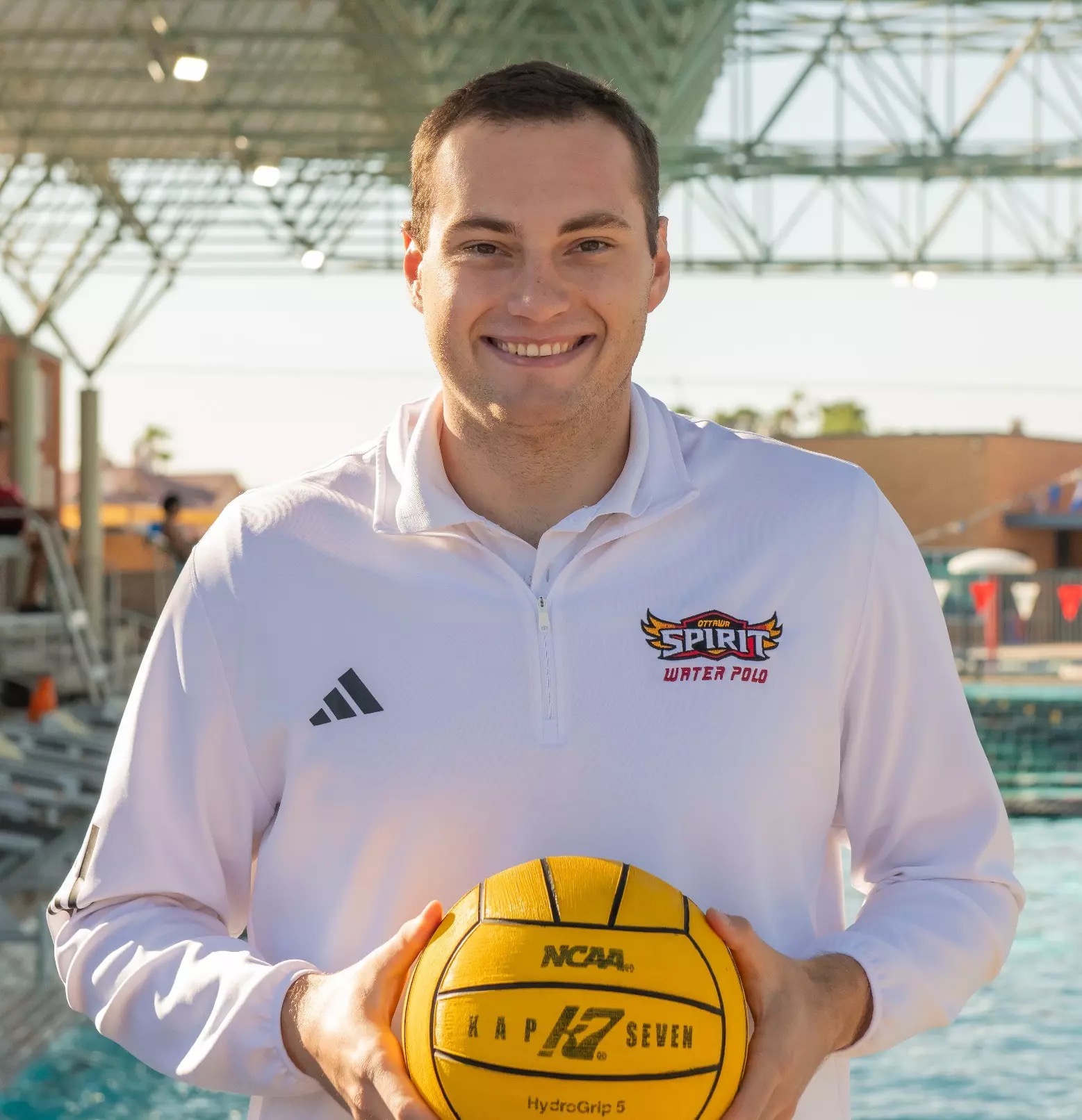 Pavle Ristić holding a yellow water polo ball at the pool